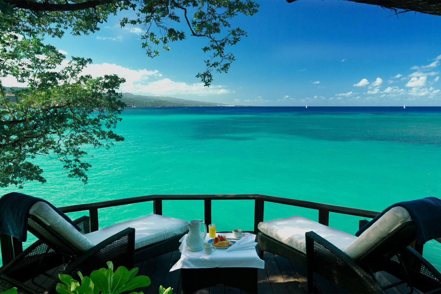 Deck with two cahirs overlooking green ocean waters