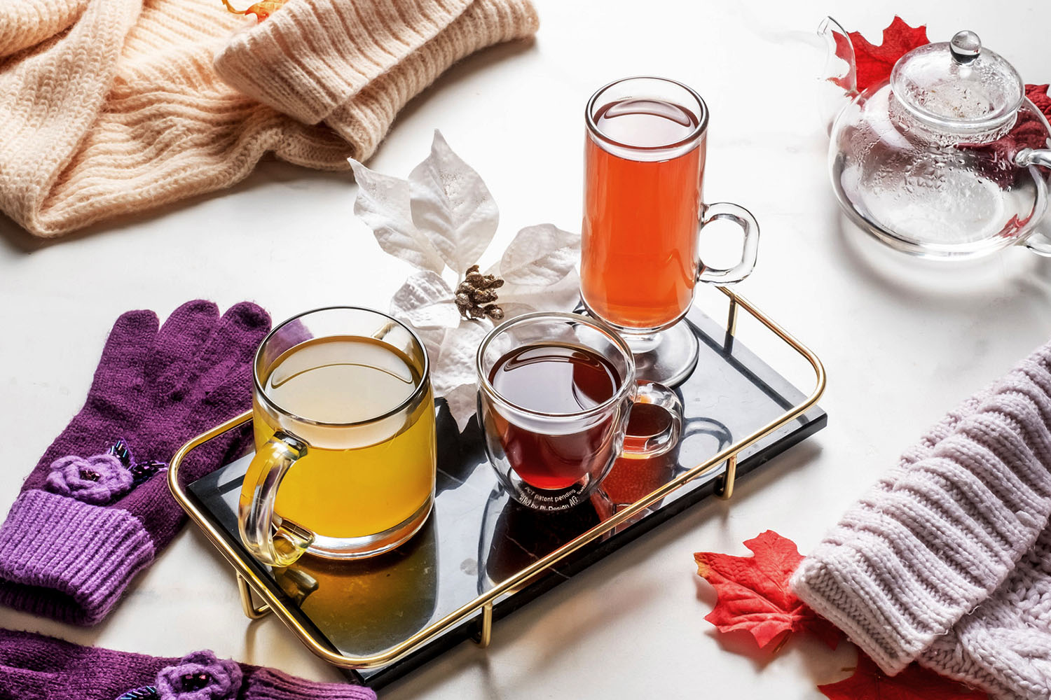 three cups of warm cocktails on a tray with flower petals