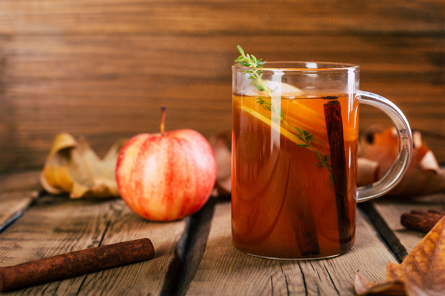 Mug of cider with cinnamon stick and apple slices