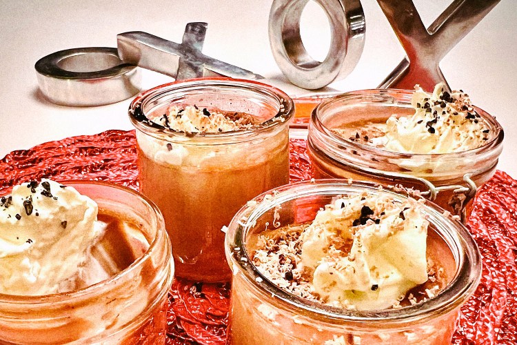 glass jars with chocolate desserts topped with whipped cream