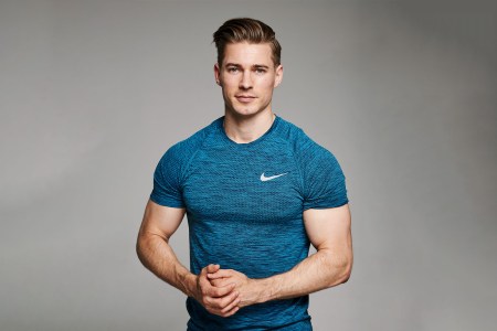 Jack Hanrahan, celebrity personal trainer wearing a blue t-shirt on a gray background