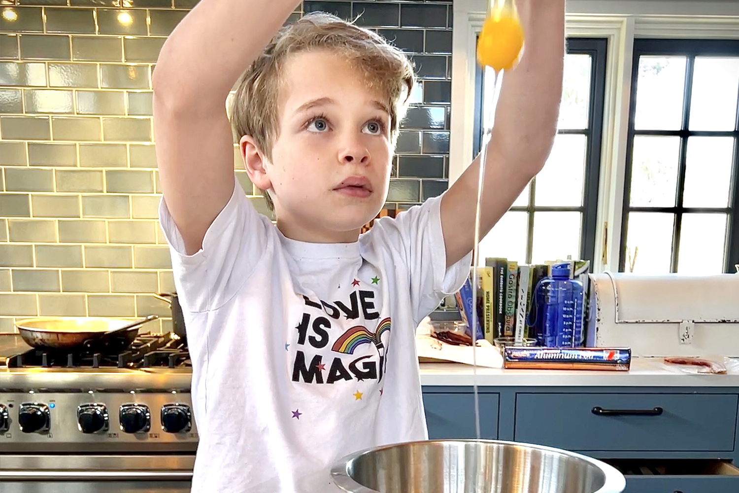 Boy breaking eggs into bowl on kitchen counter