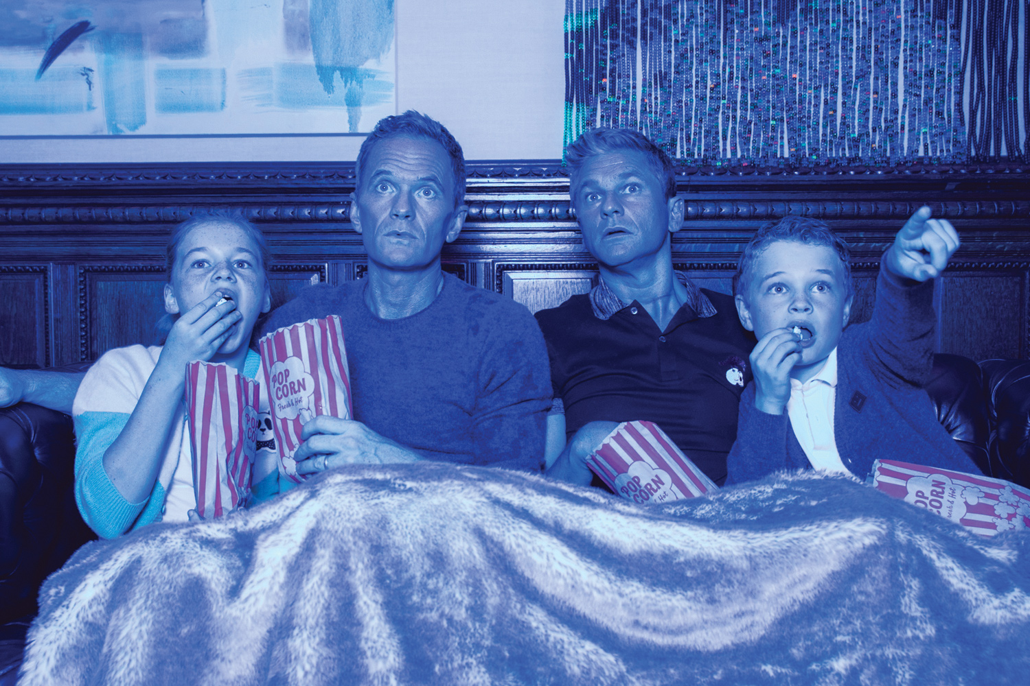 Family watching movies on couch with popcorn