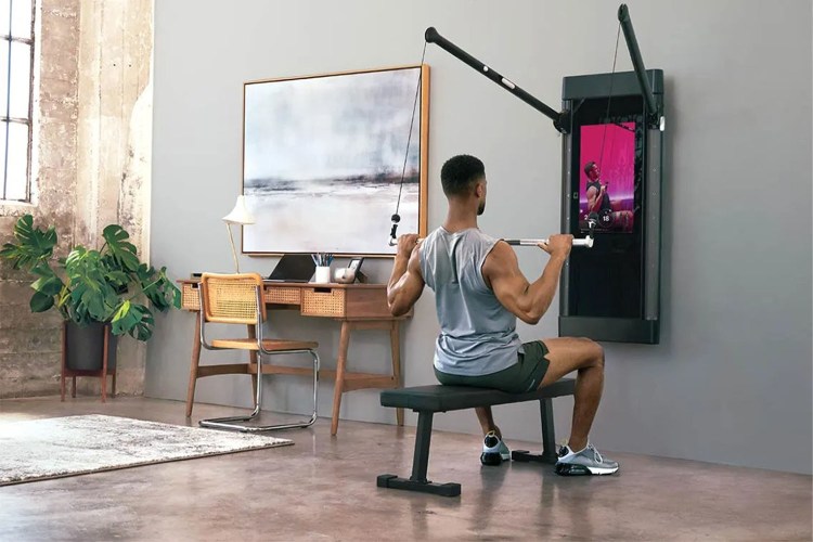 Man using Tonal next to a desk and painting in a room with a concrete floor