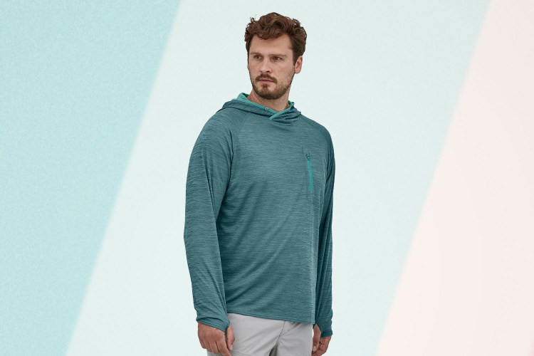 Man wearing a blue Patagonia Sunshade Technical Hoody on a background with a white and blue background