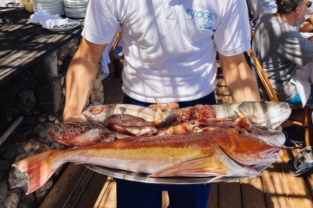 Man holding a tray of fish at restaurant in Italy