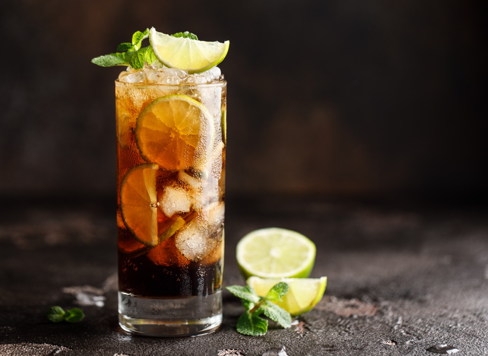 Cuba Libre with brown rum, cola, mint and lime. Cuba Libre or long island iced tea cocktail with strong drinks