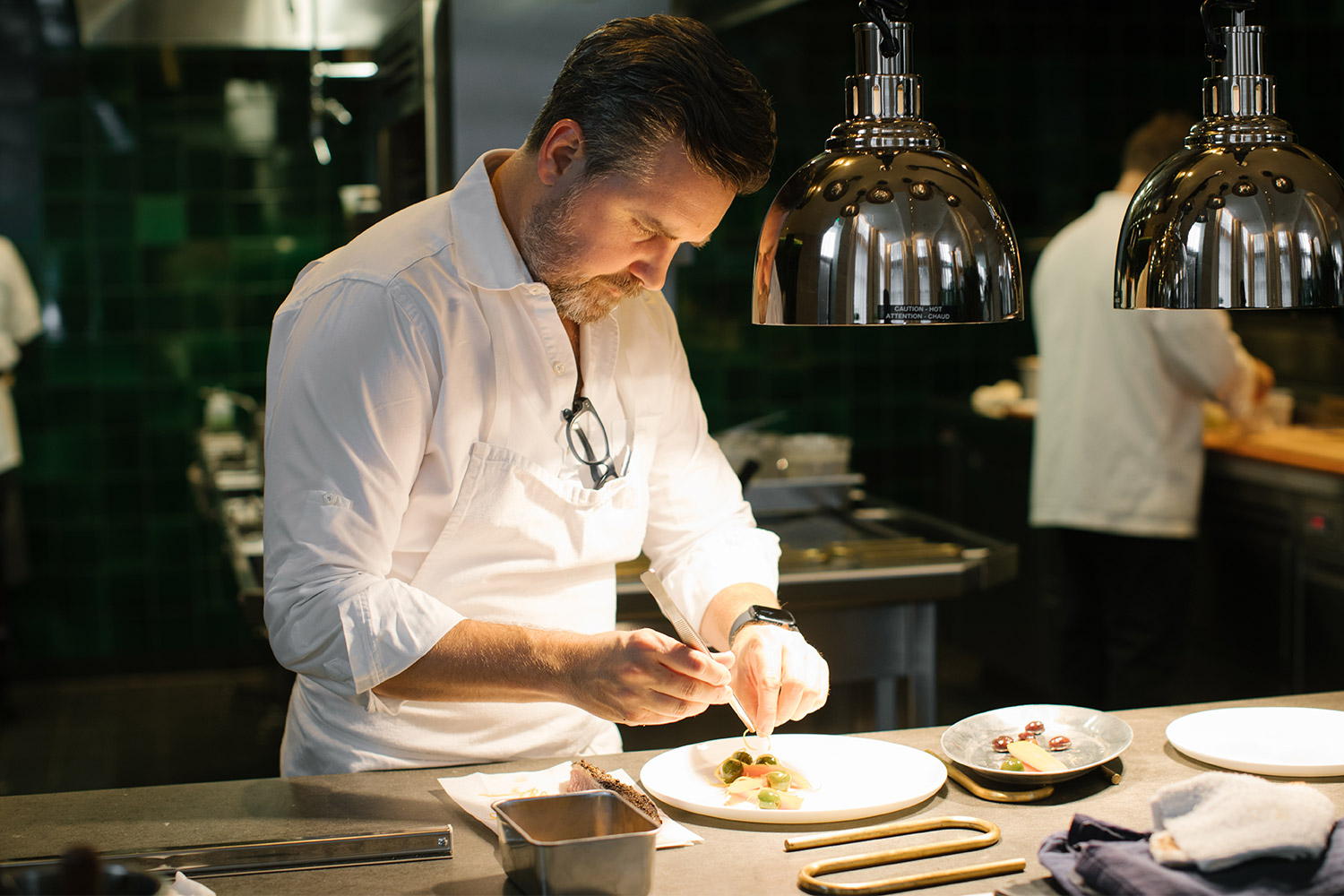 Chef John Fraser preparing a dish in a kitchen