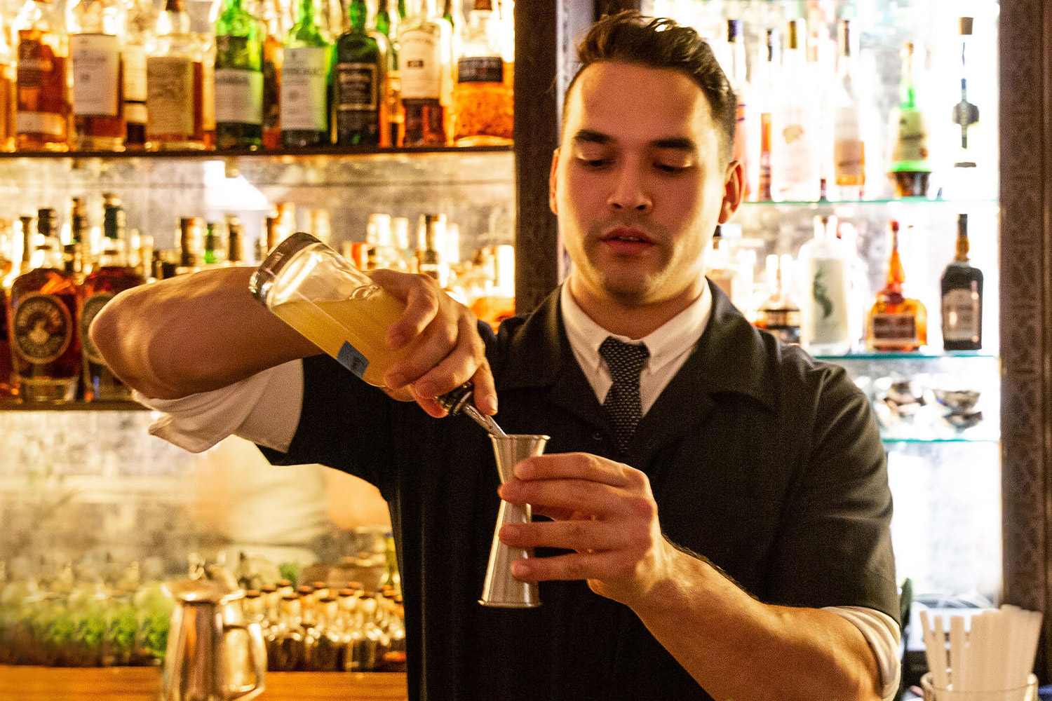 Jonathan Lind pouring and mixing drinks at a bar
