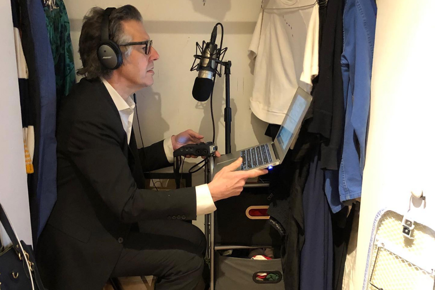 Ira Glass reading his show This American Life in his closet dressed in a suit