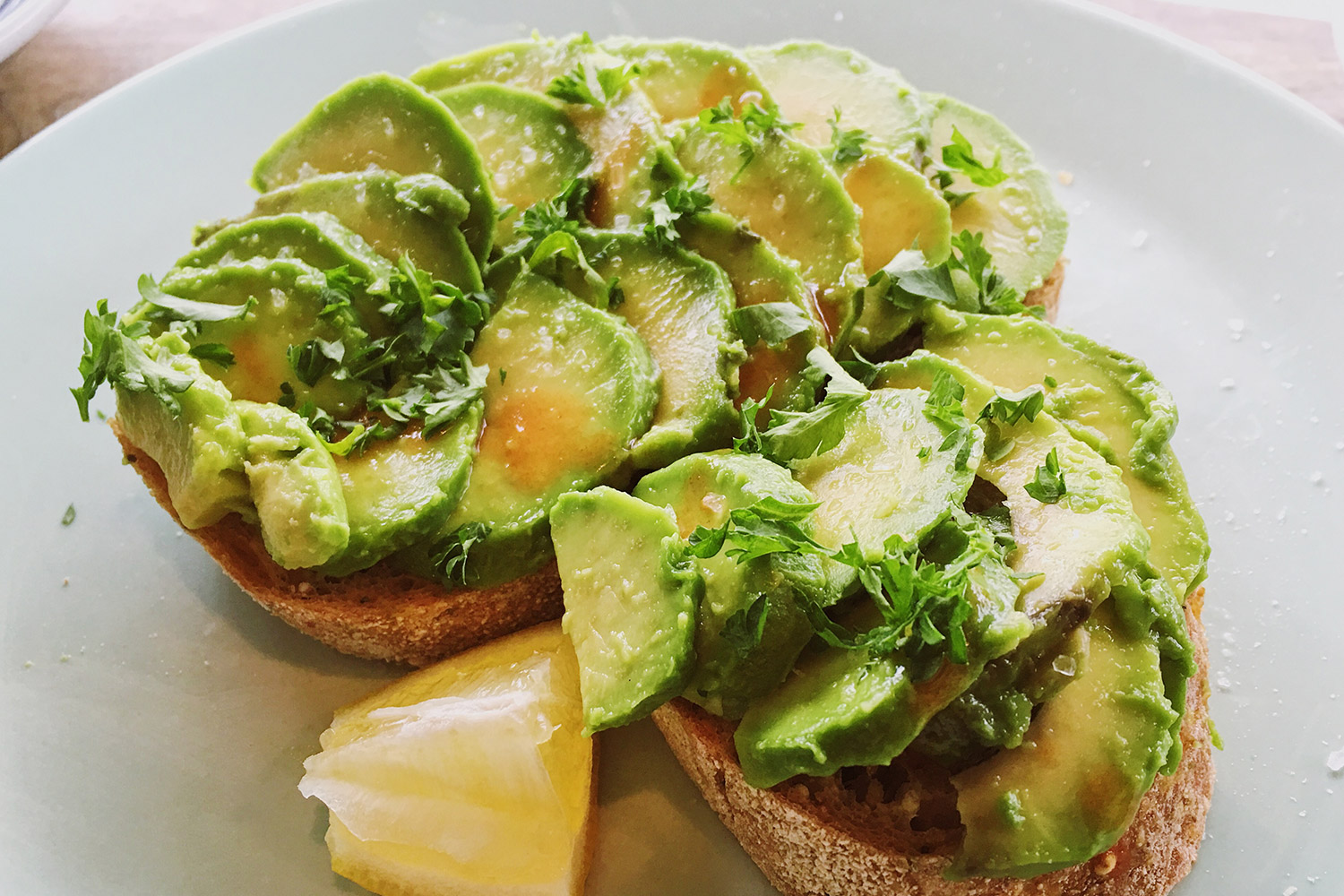 Avocado toast with cilantro and parsley on white plate
