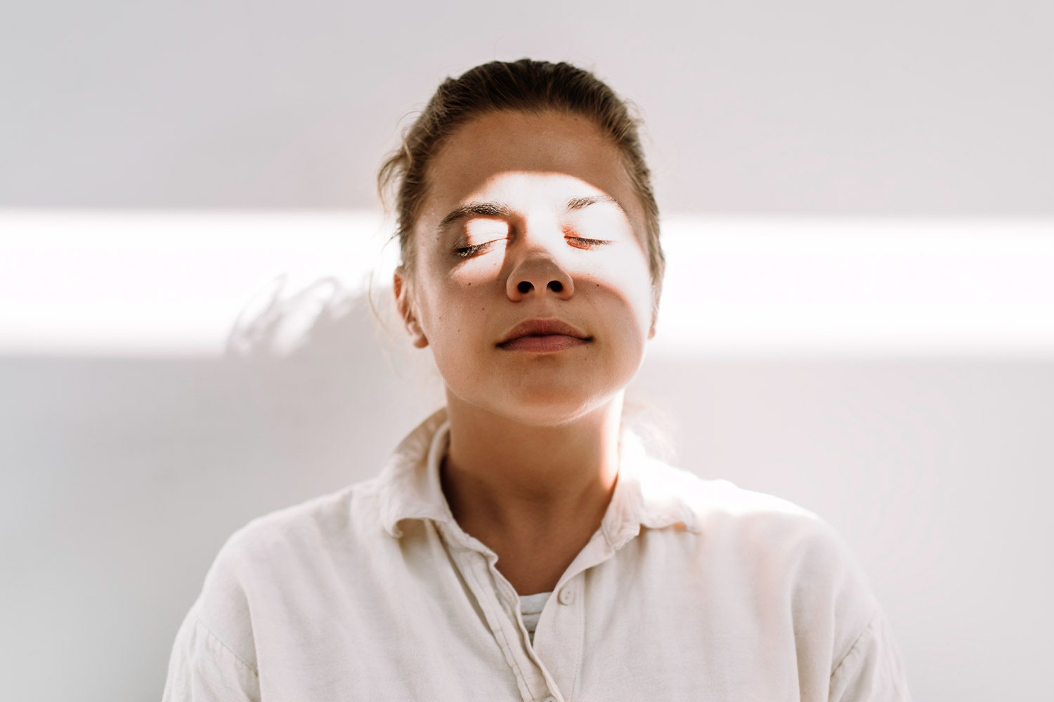 Woman practicing deep breathing in front of beige wall