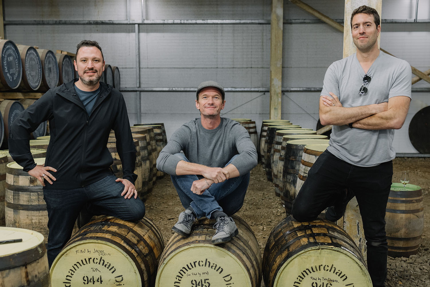NPH sitting on barrels with two other men