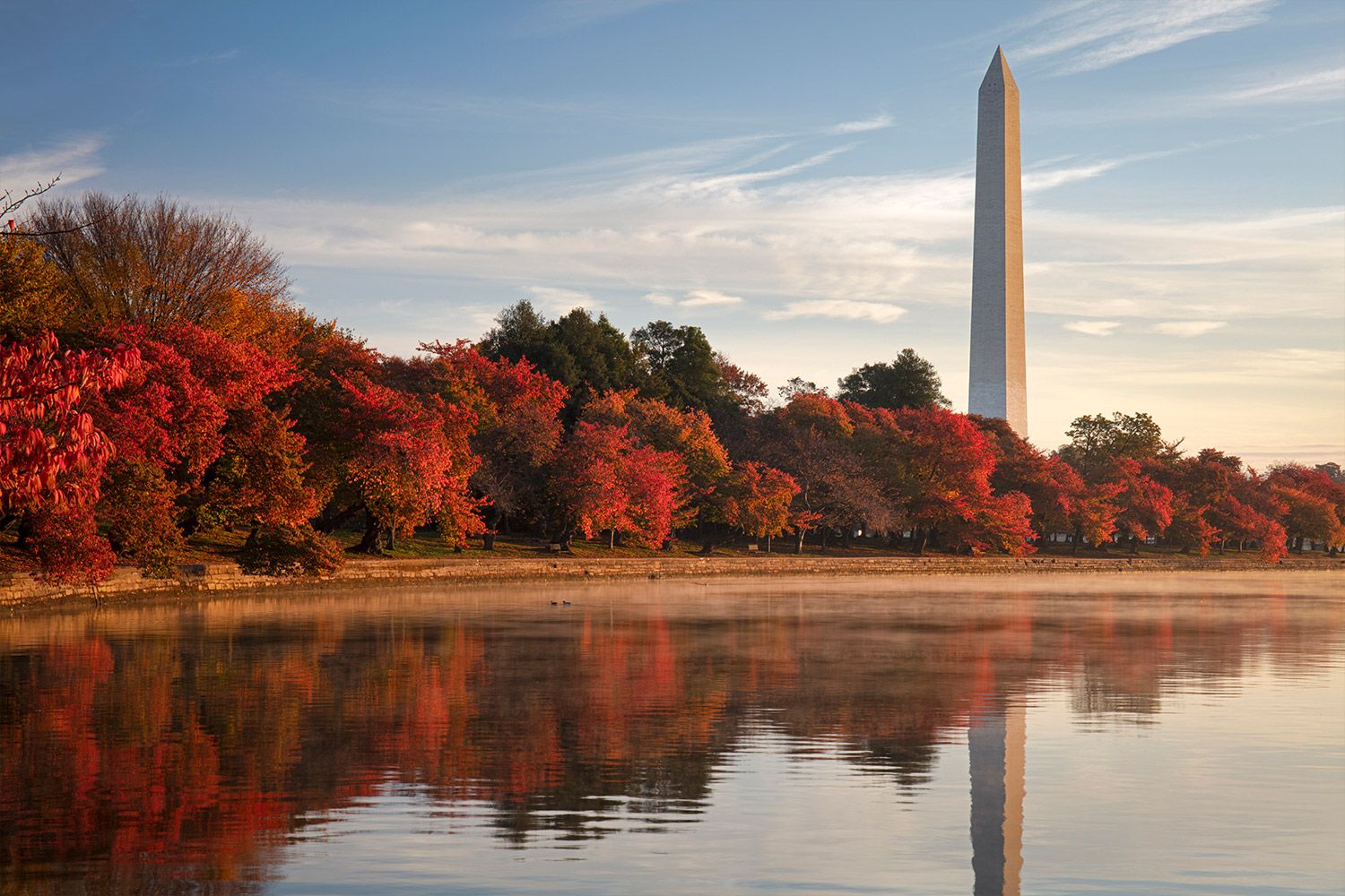 View of red trees and the Washington Monument with scene reflecting on the water