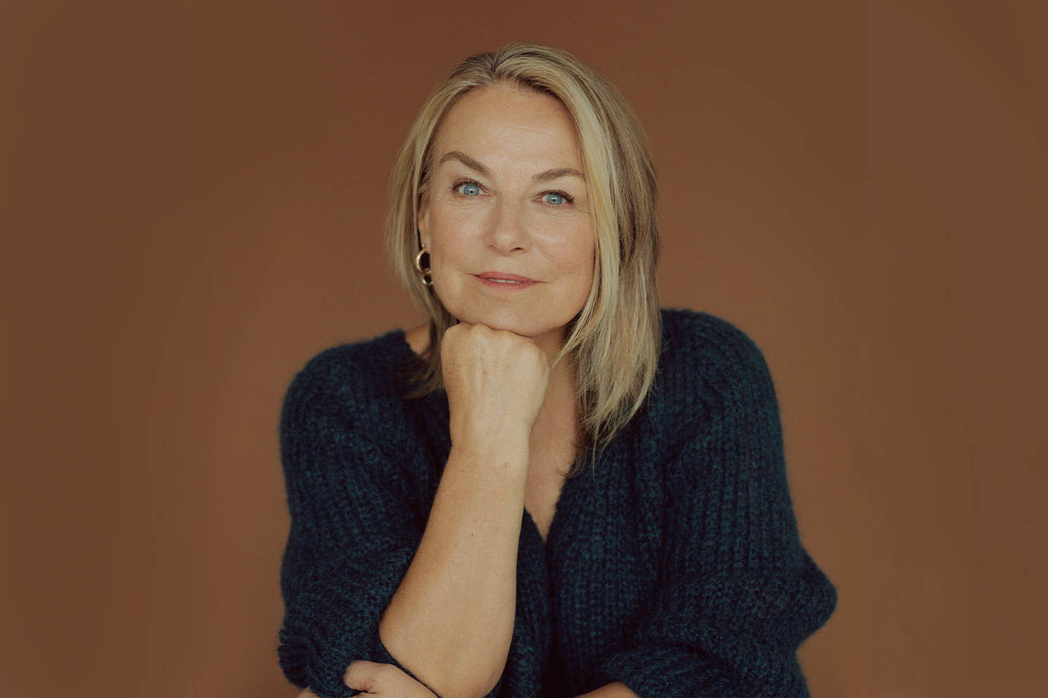 Ester Perel posing for professional photo on brown background with chin resting on fist