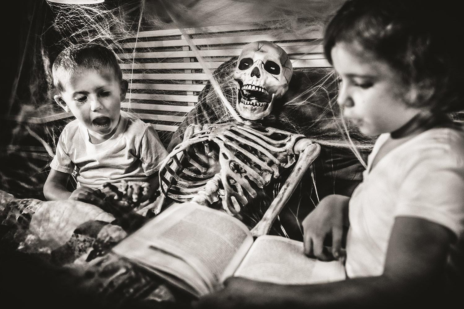 Young kids reading a book next to a skeleton