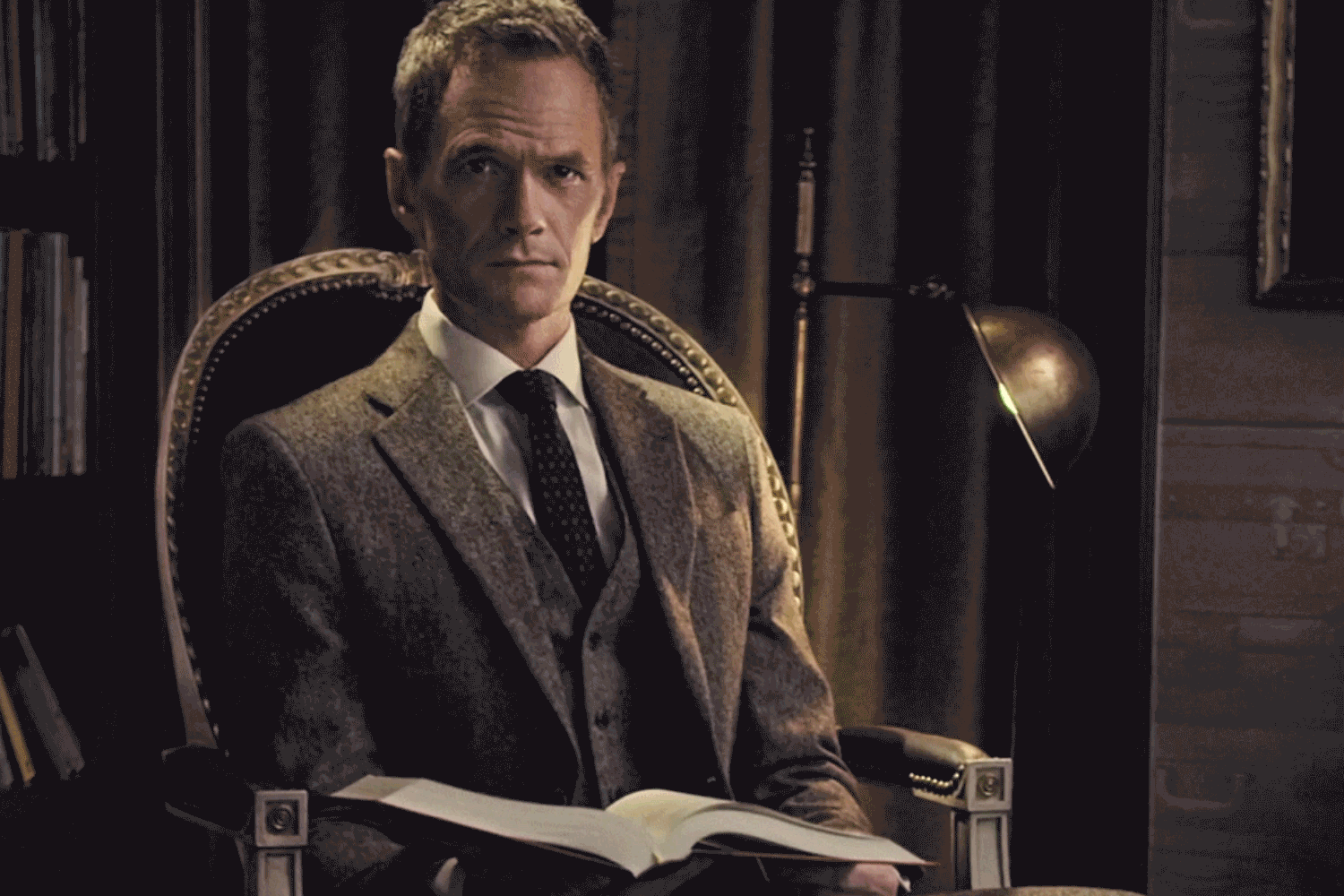 NPH sitting in a chair with book
