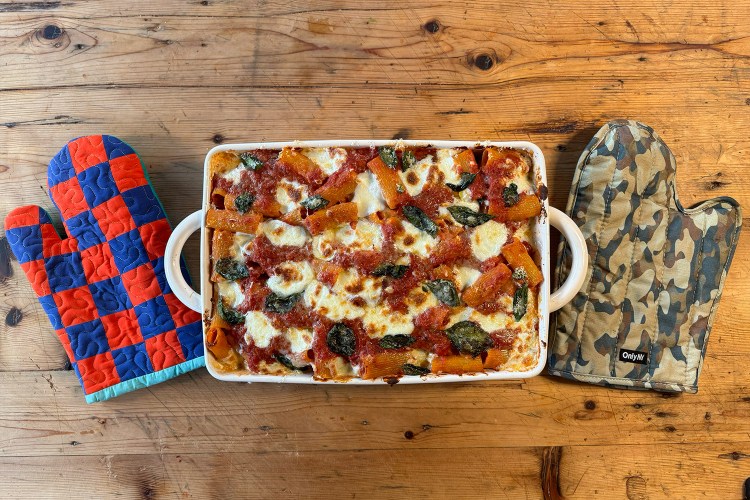 Baked Ziti from above with a checkered oven glove and camo oven glove