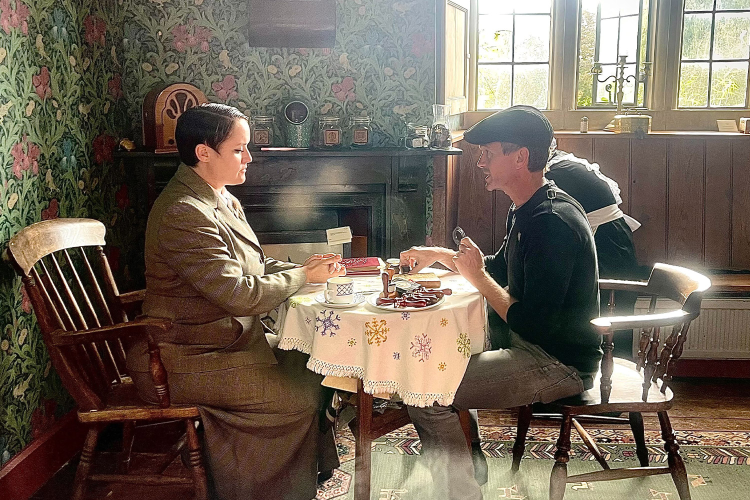 Neil Patrick Harris sits across from a person in a suit at a small tea table