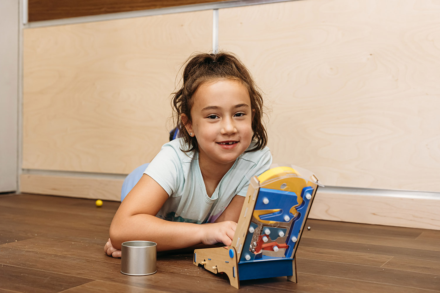 A girl in ponytail lays on the floor playing with a game