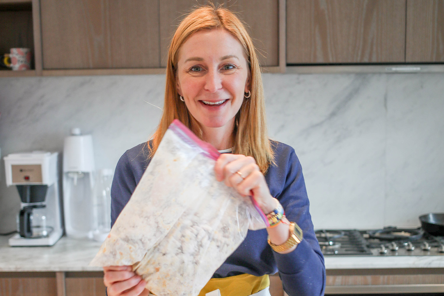 Woman stands in kitchen holding plastic bag filled with puppy chow