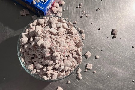 View from above of a bowl filled with puppy chow on a stainless steel countertop