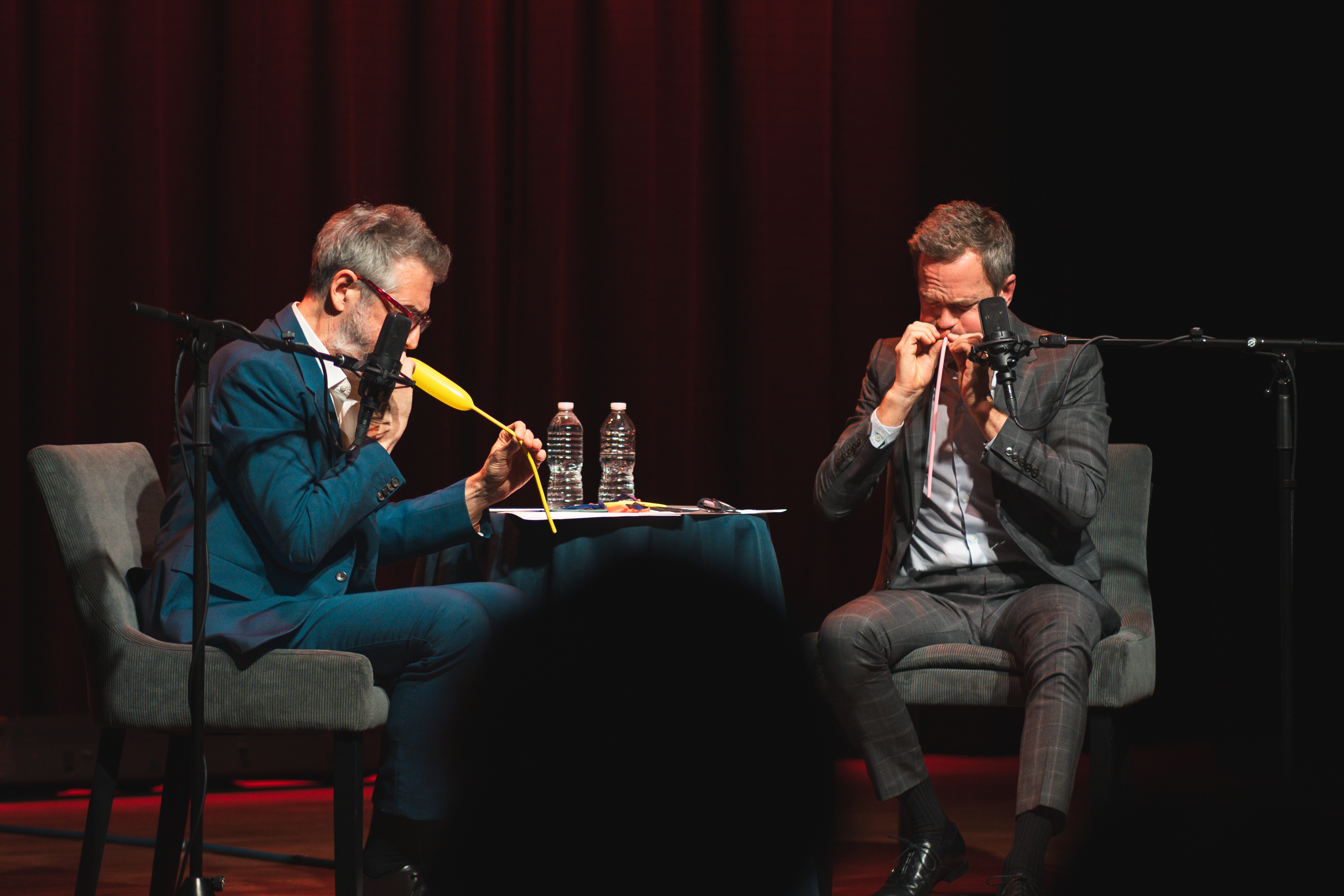 Neil Patrick Harris and Ira Glass blowing up balloon animals on stage