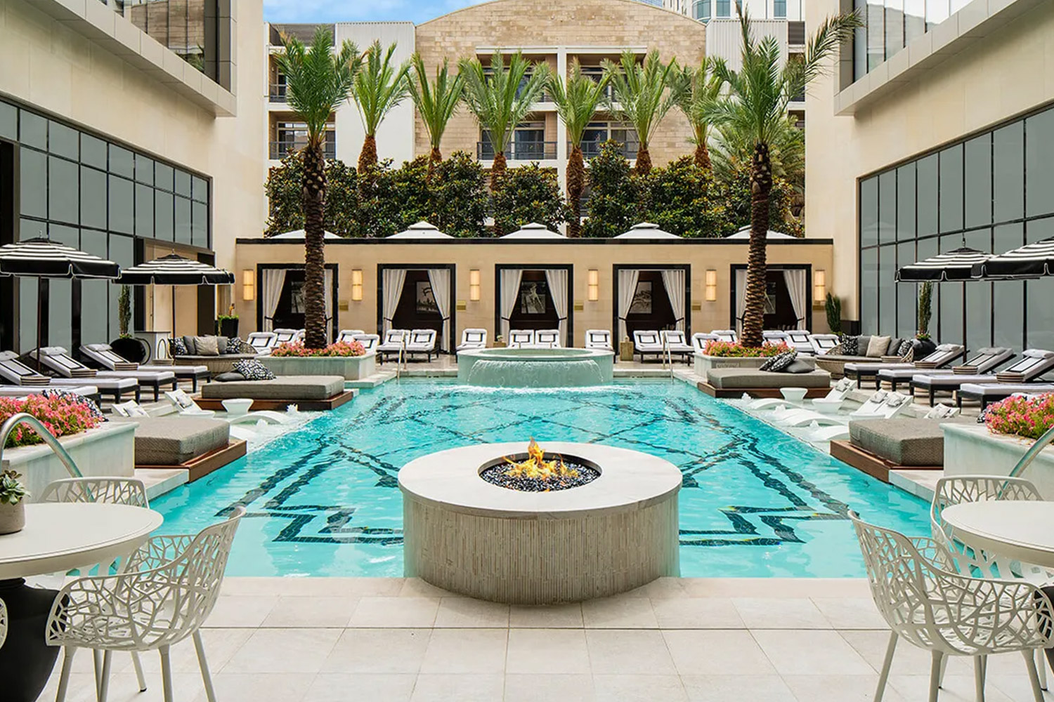 Modern hotel pool surrounded by lounge chairs and fire fit