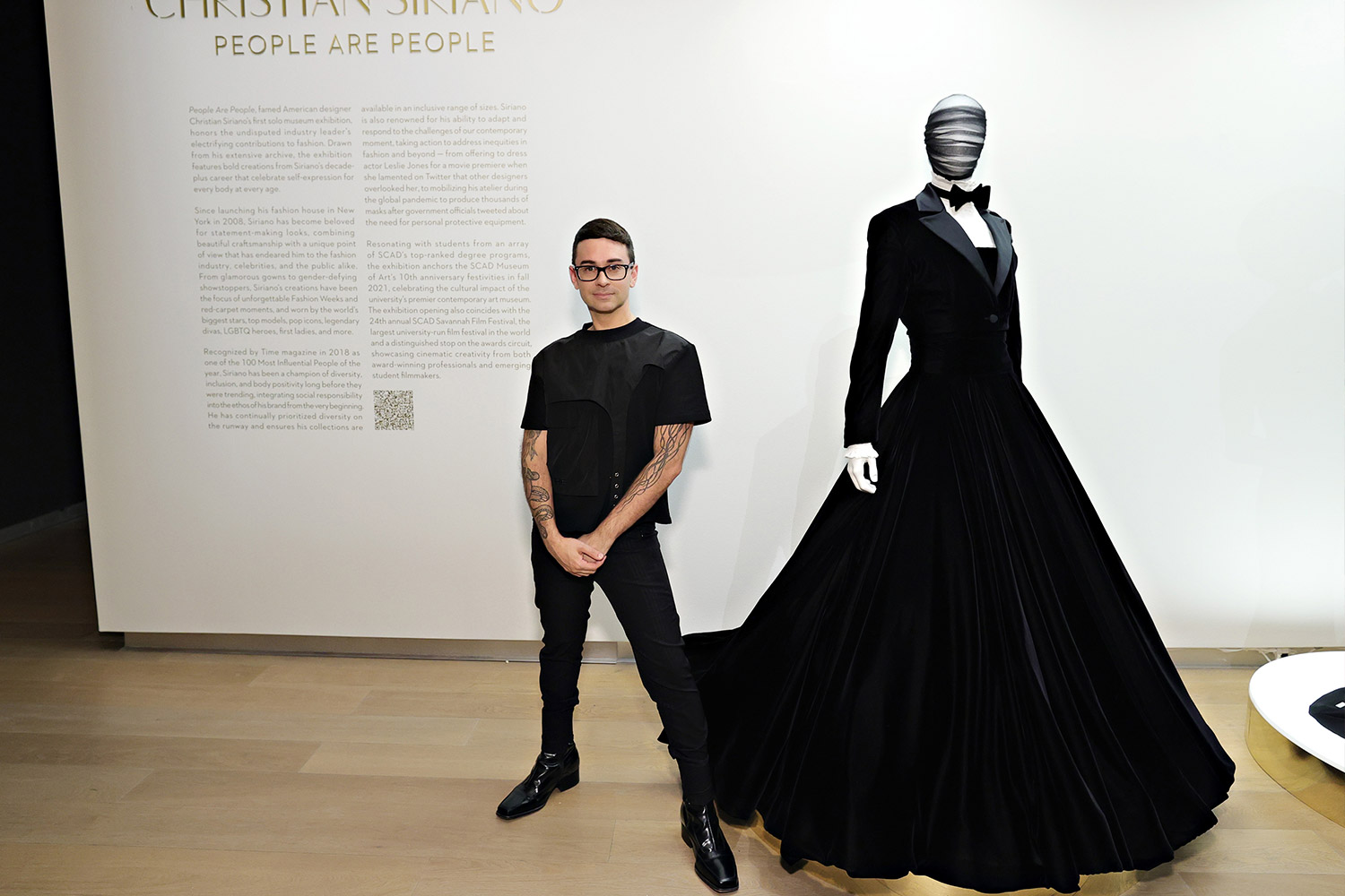 Designer stands next to a tuxedo dress in his museum exhibit