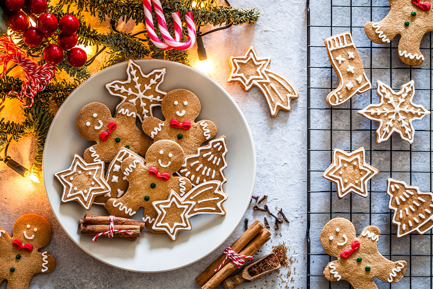 Gingerbread cookies decorated with icing in a bowl surrounded by holiday decor