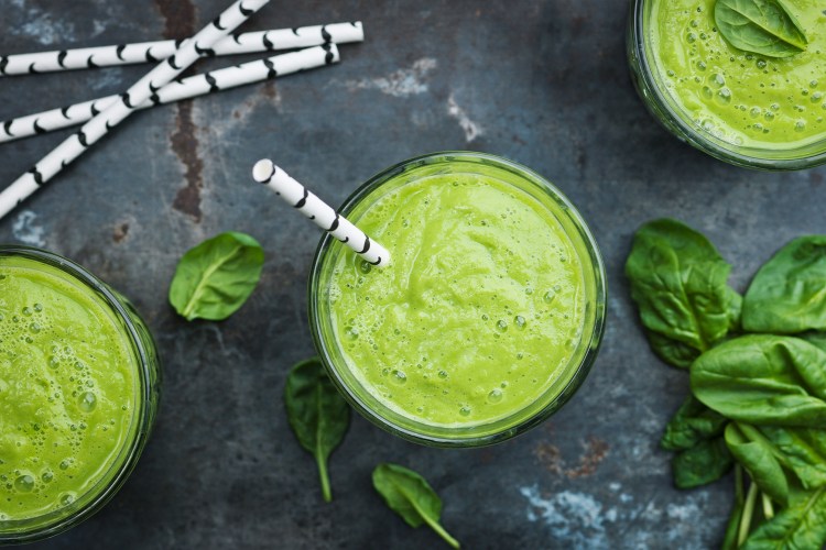 Green smoothie from above with spinach surrounding it