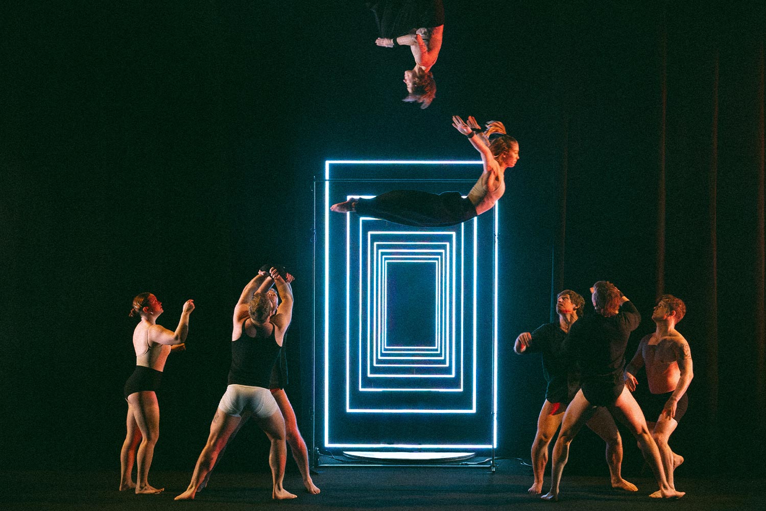 Acrobats perform in front of neon rectangles