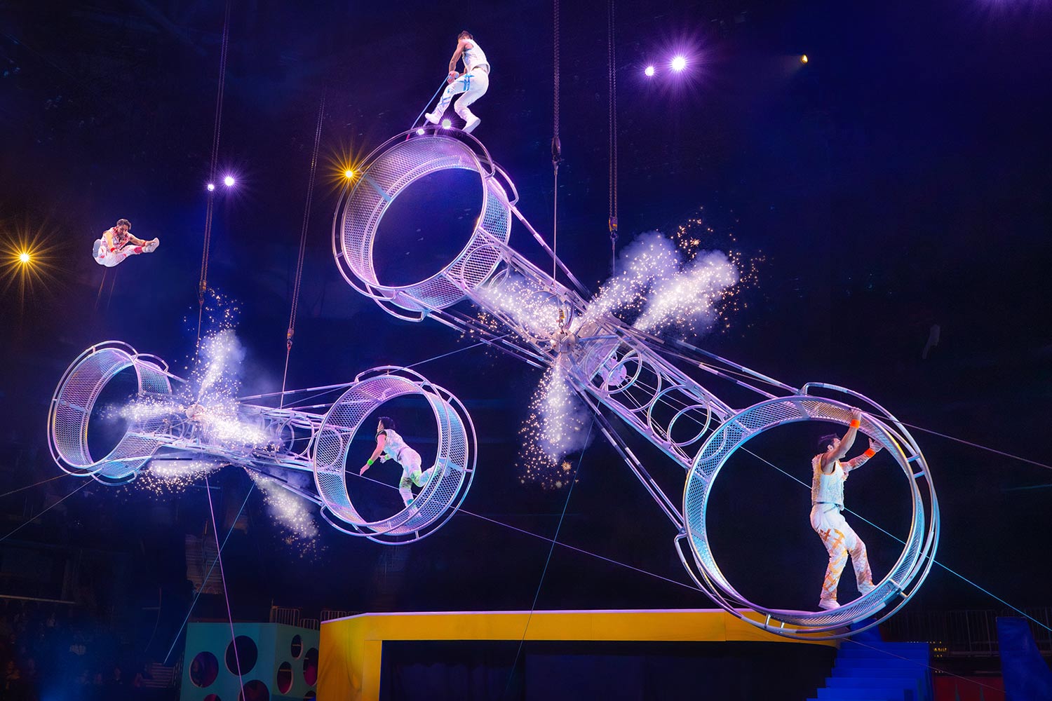 Acrobats riding a giant spinning wheel and flipping