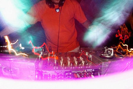 Artistic photo of a DJ spinning his turn table with bright lights