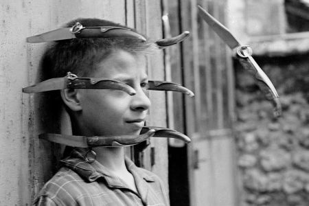 Boy against wall with knives surrounding his head