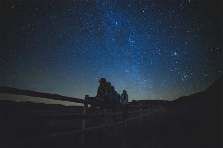Kids sitting on a fence gazing at the stars