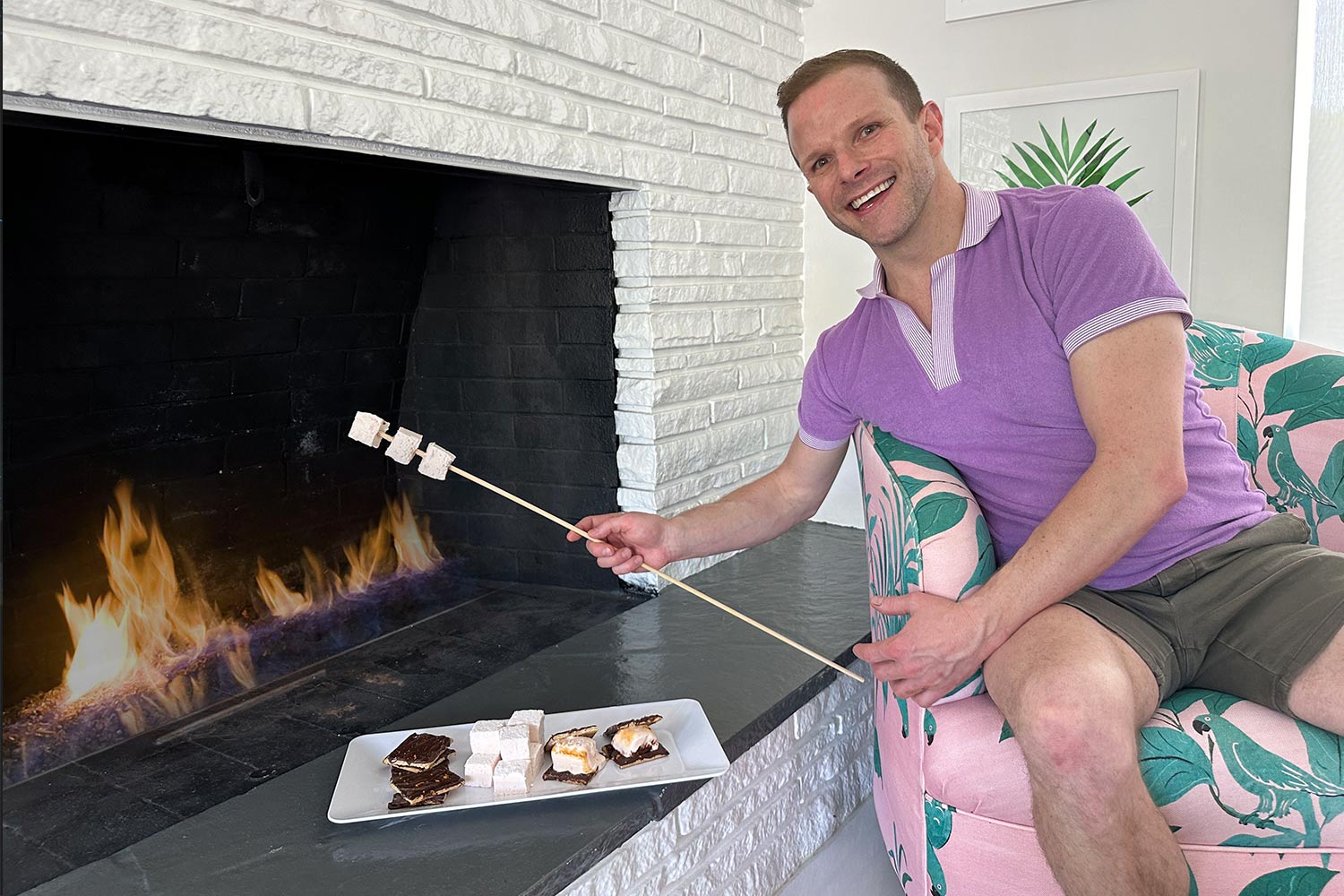 Zac Young roasting marshmallows on a stick over an indoor fireplace